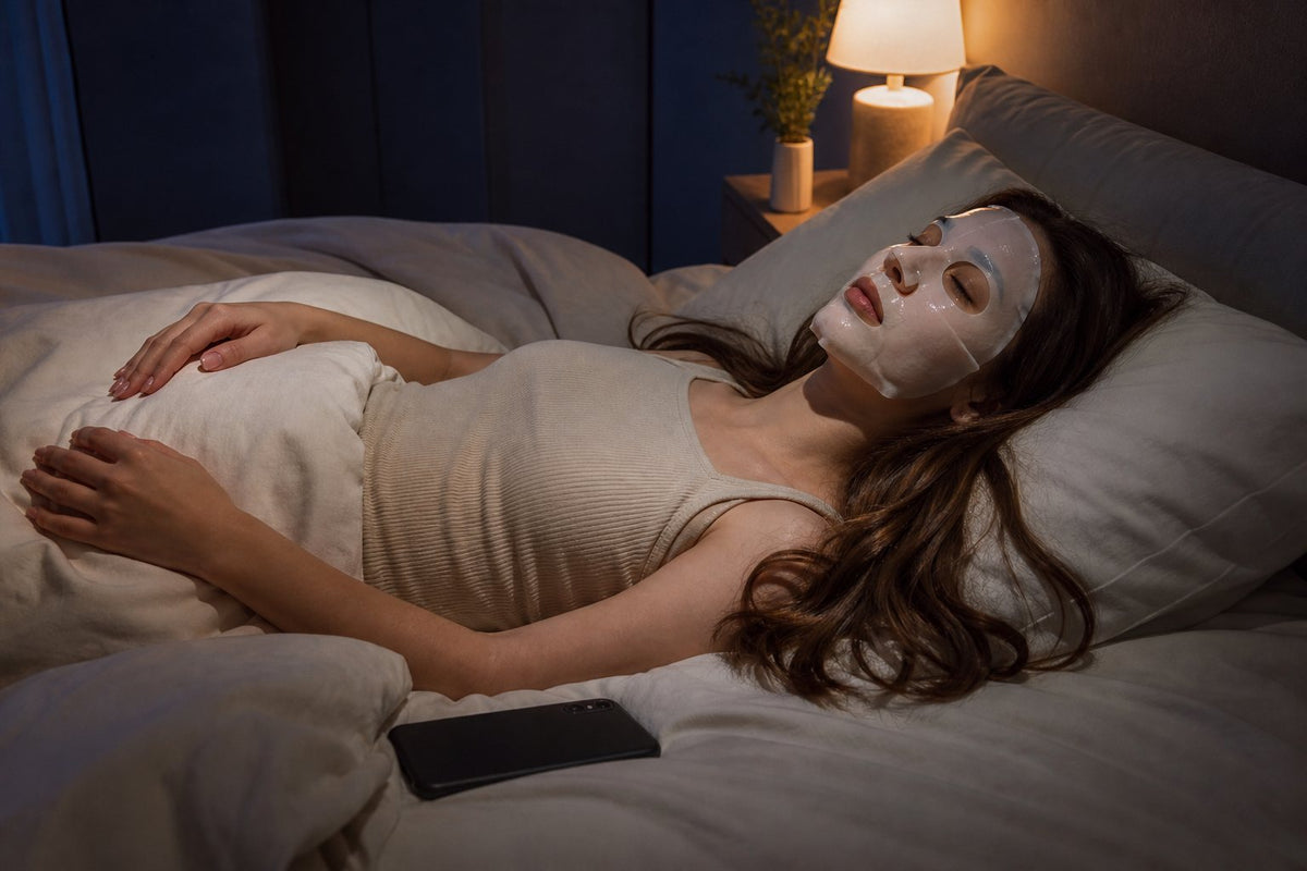 girl lying on her bed wearing the mask, phone face-down